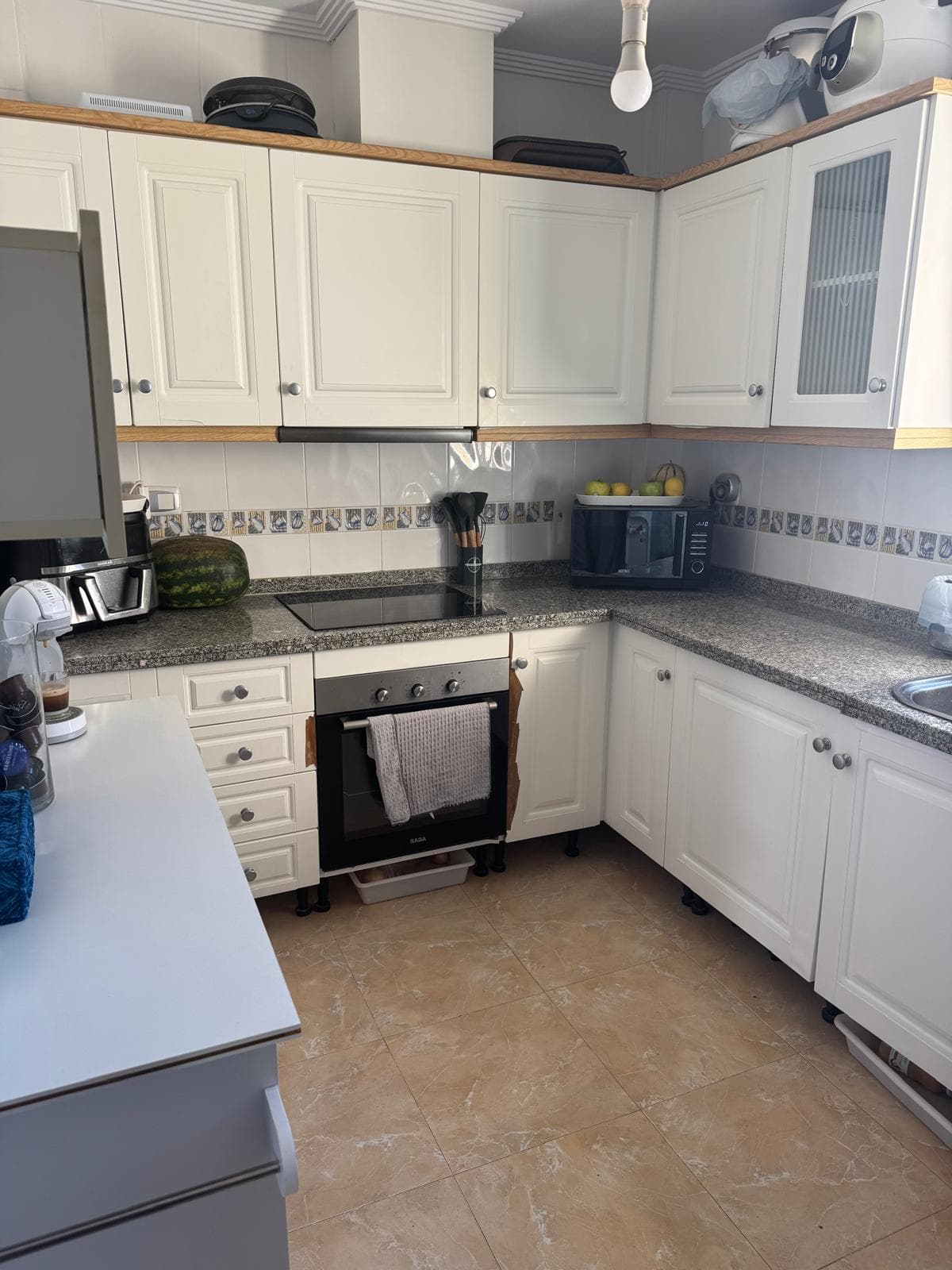 Cuisine équipée vue depuis l’entrée avec rangements blancs